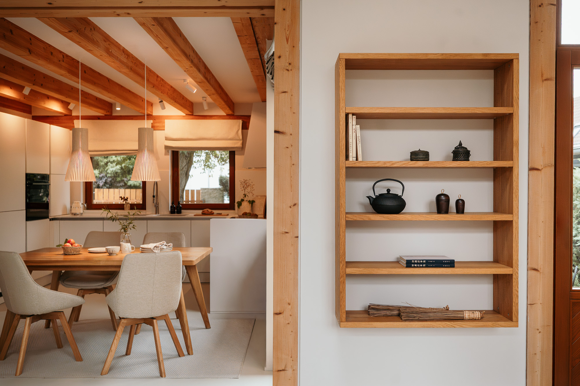 Offene Küche mit Holzbalkendecke, Pendelleuchten und Wandregal