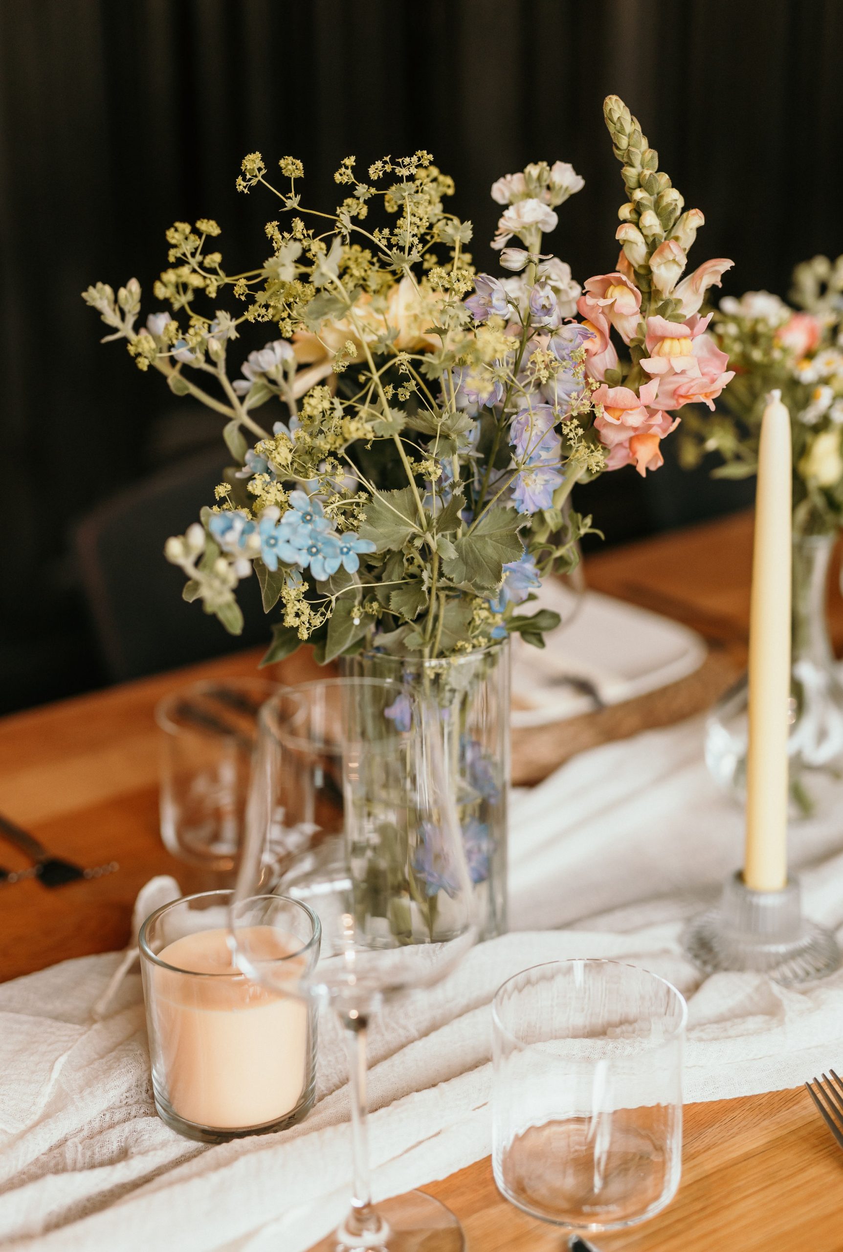 Tischdekoration bei einer Hochzeit in Osthofen bestehend aus Blumen in Glasvasen, Tischläufer und Kerzen