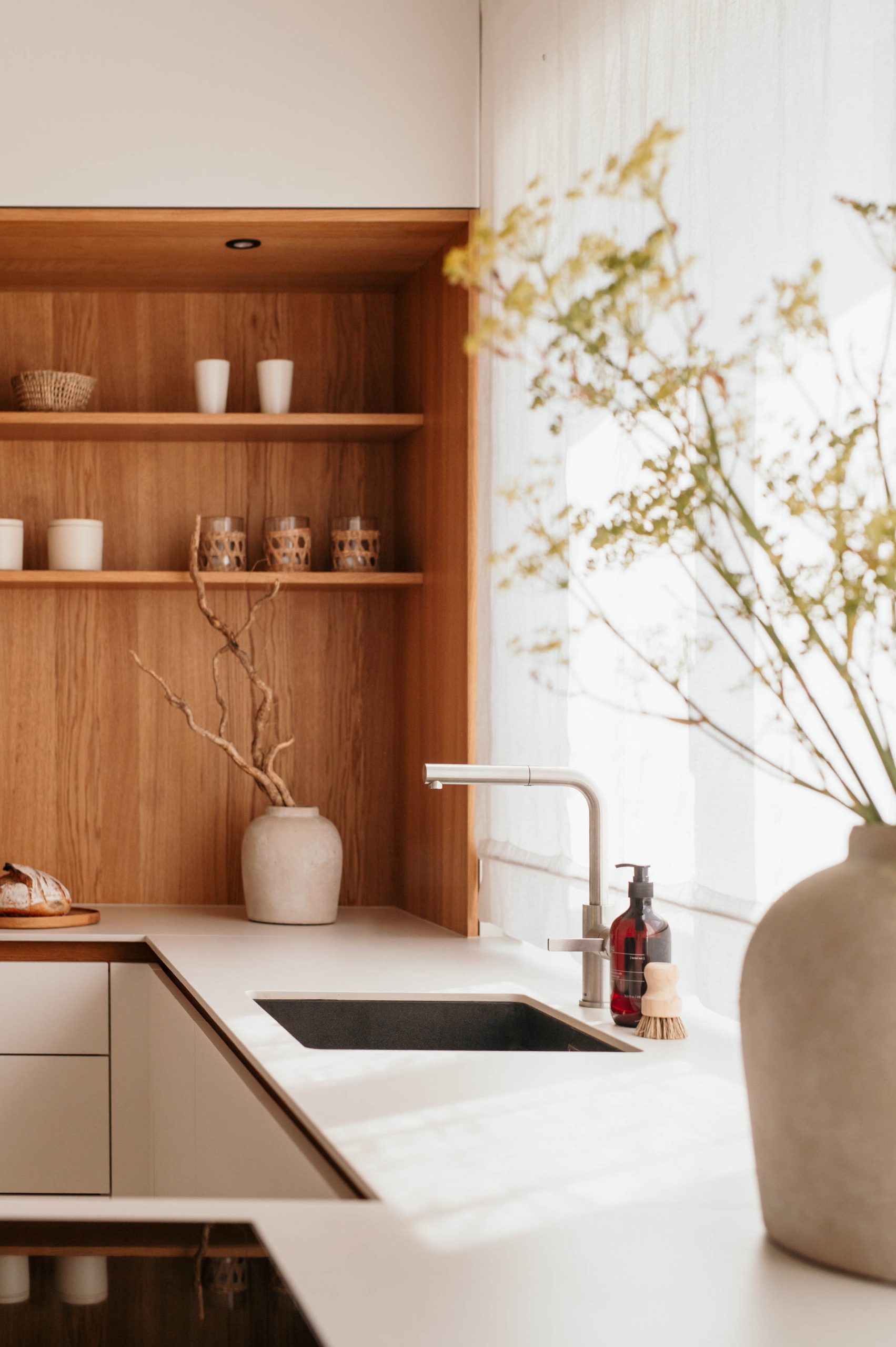 Küchenzeile mit Holzregal, Keramikvase und Wasserhahn