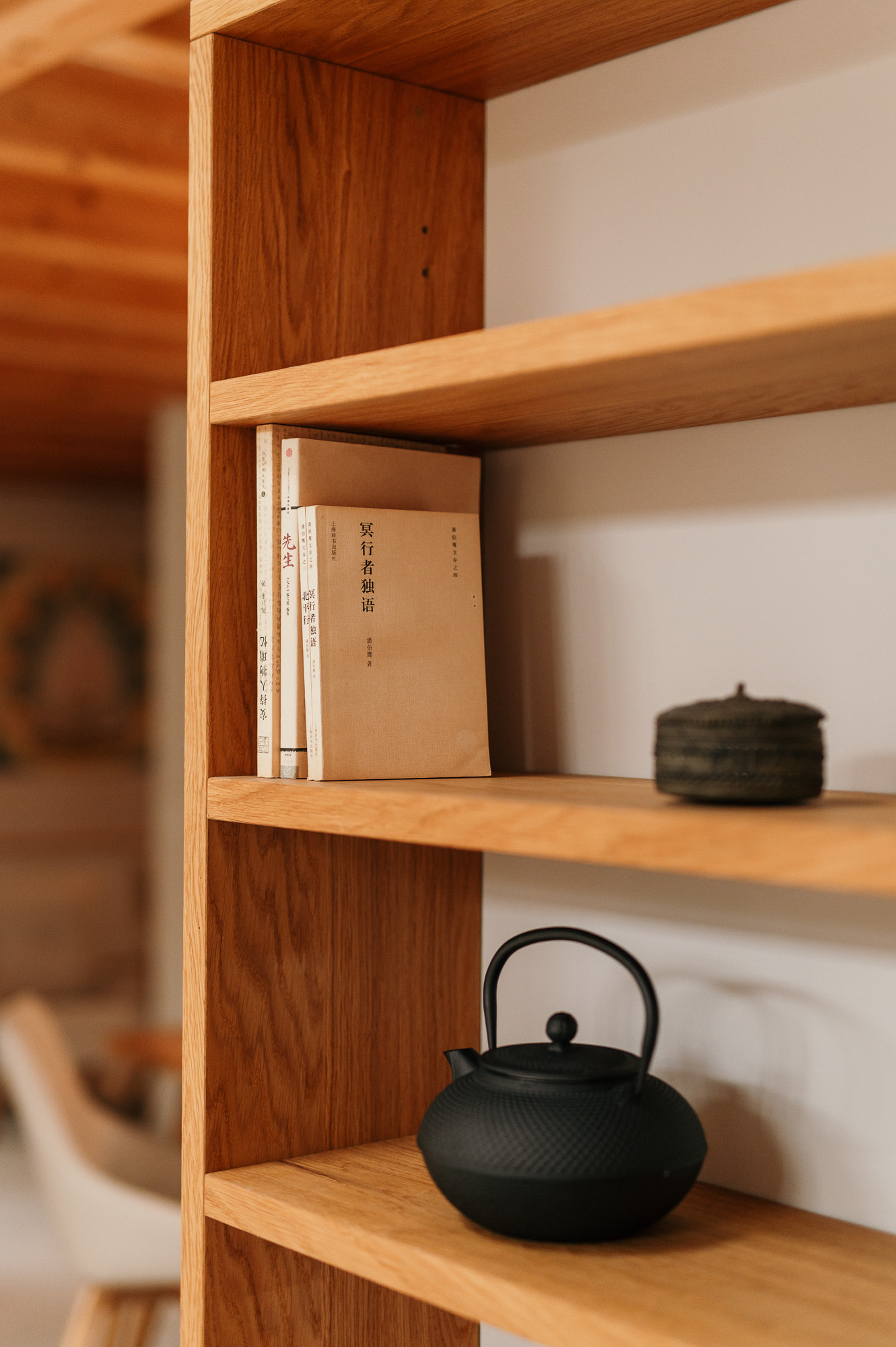 Holzregal mit Büchern, Deko und einer schwarzen gusseisernen Teekanne