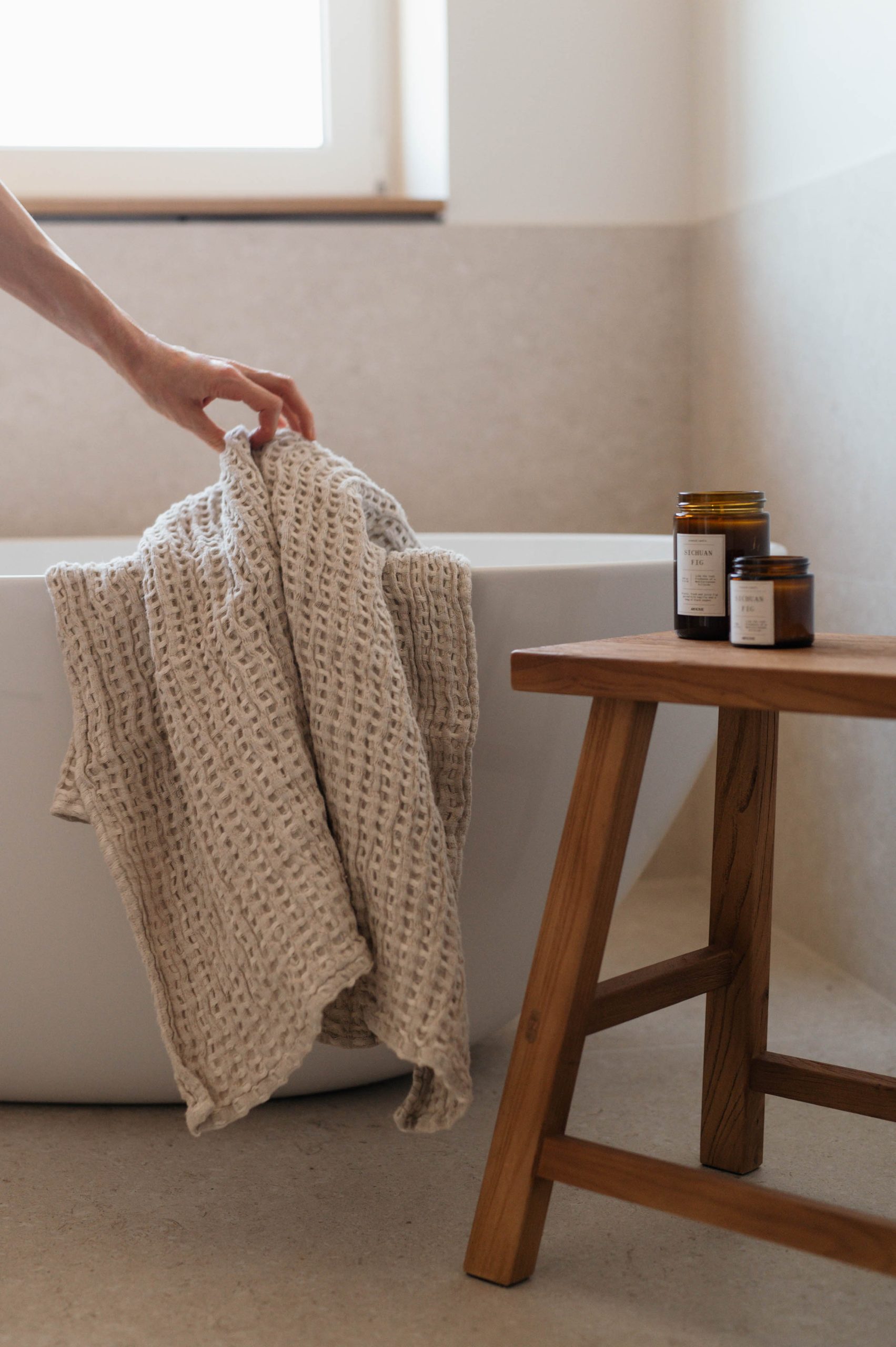Detailshot von Handtuch und Hand auf freistehender Badewanne in minimalistisch gestaltetem Bad - Interior-Fotografie Mannheim