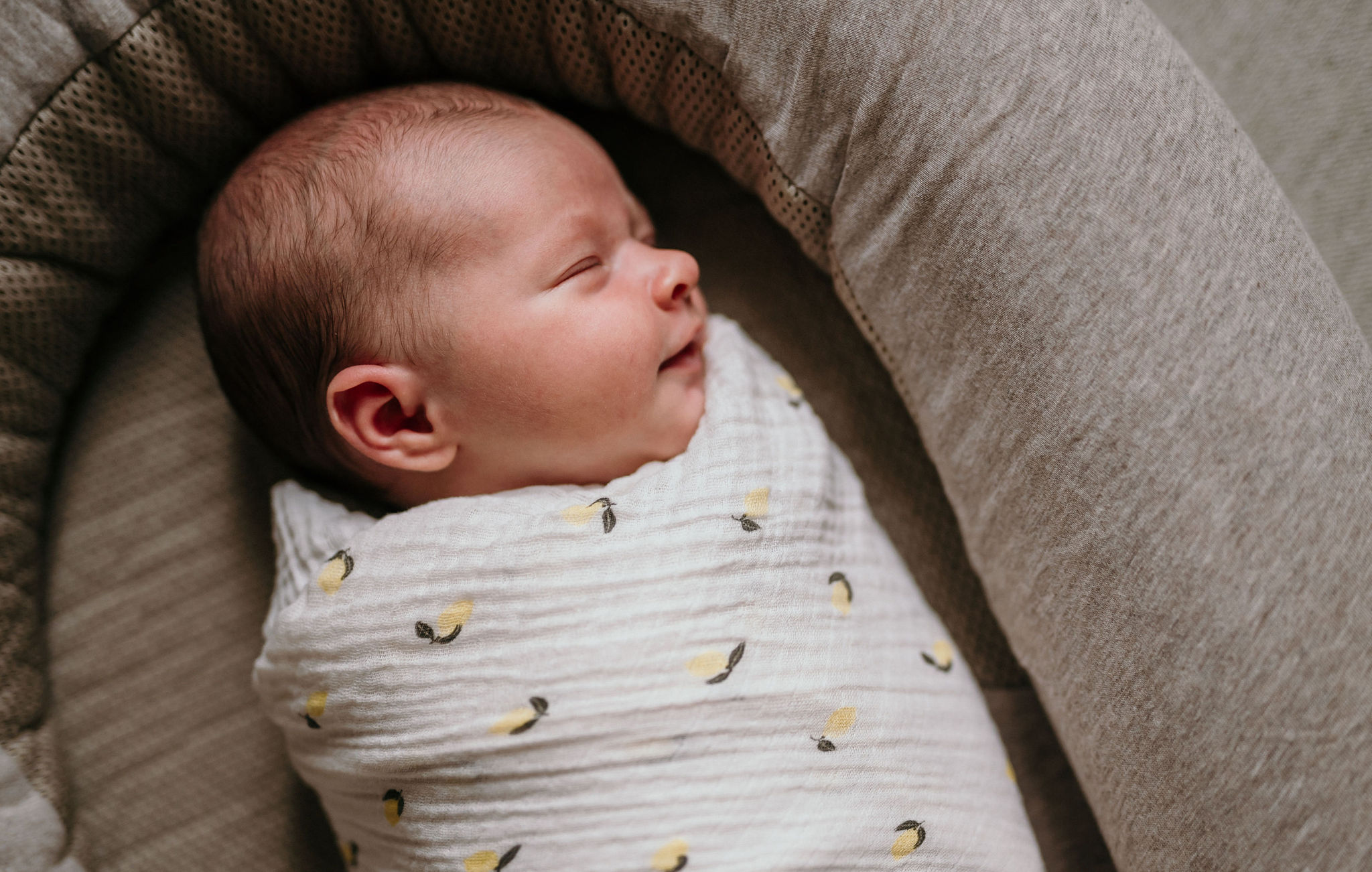 Gepucktes Neugeborenes schläft im Babynest, Seitenansicht im weichen Fensterlicht