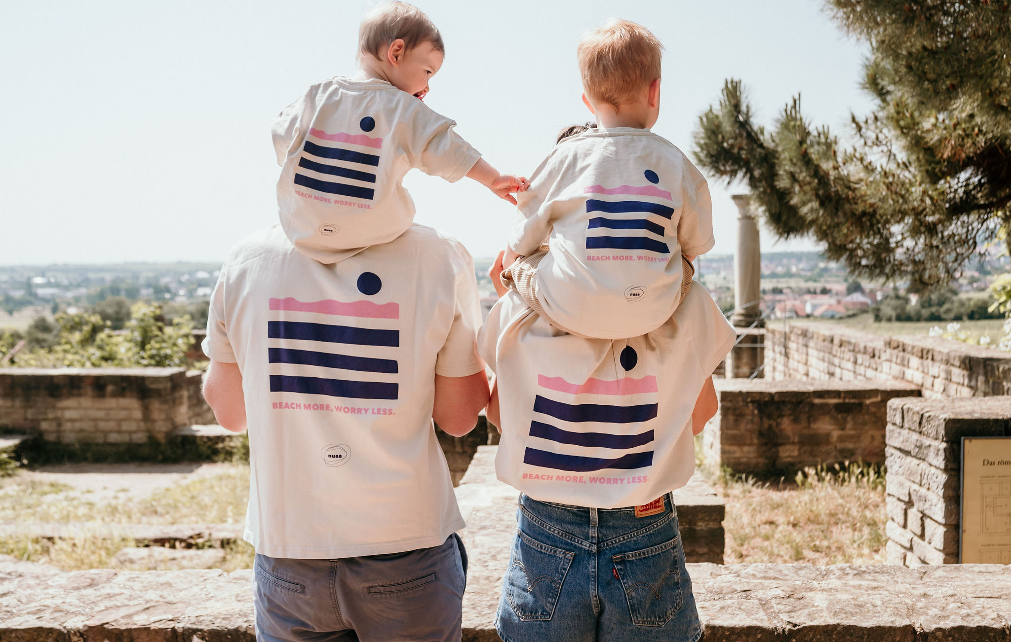 Familie ist von hinten zu sehen mit matching Shirts bei Familienshooting in Bad Dürkheim im Sonnenschein in den Weinbergen
