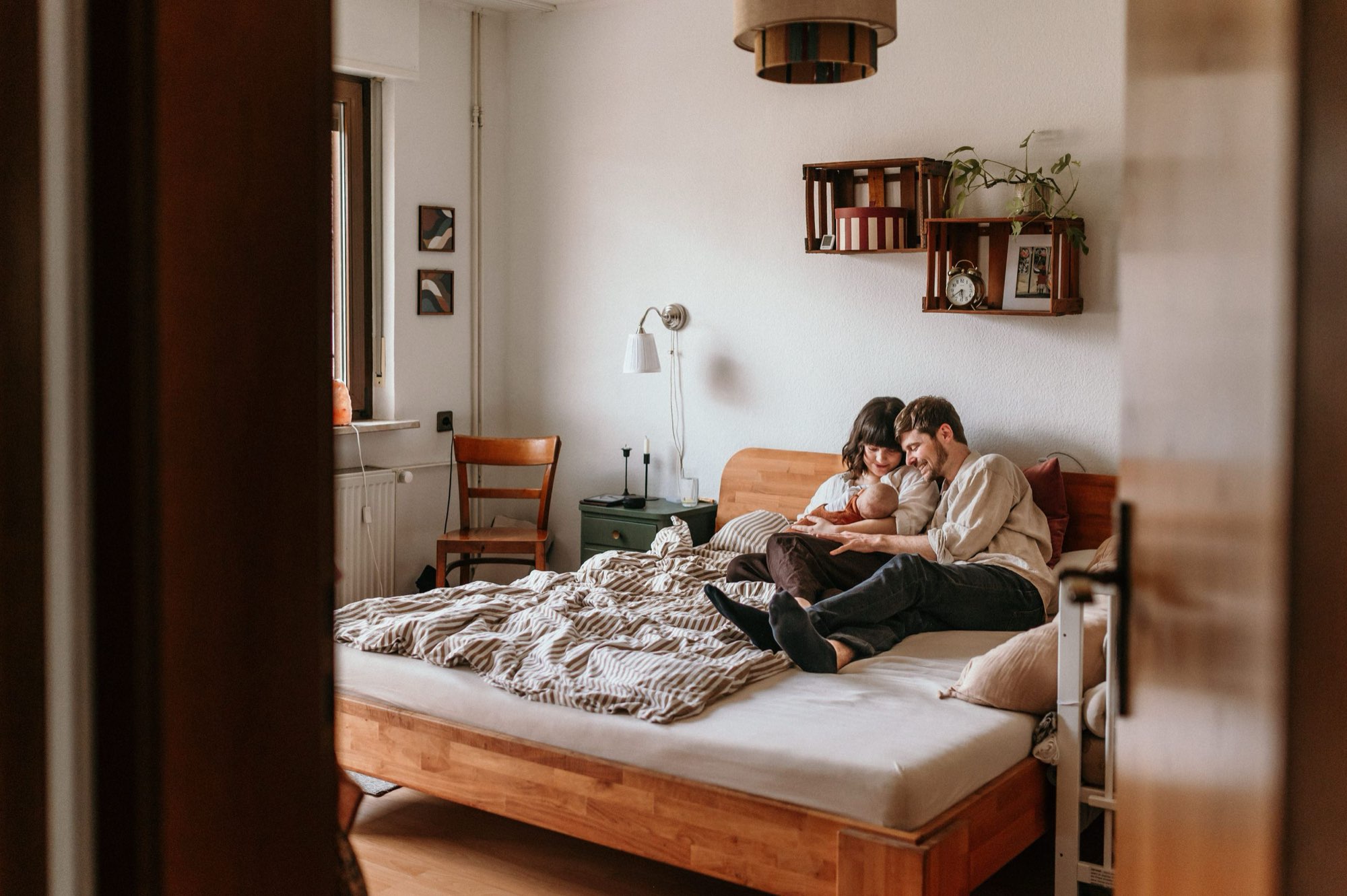 Eltern sitzen mit ihrem Baby gemütlich auf dem Bett