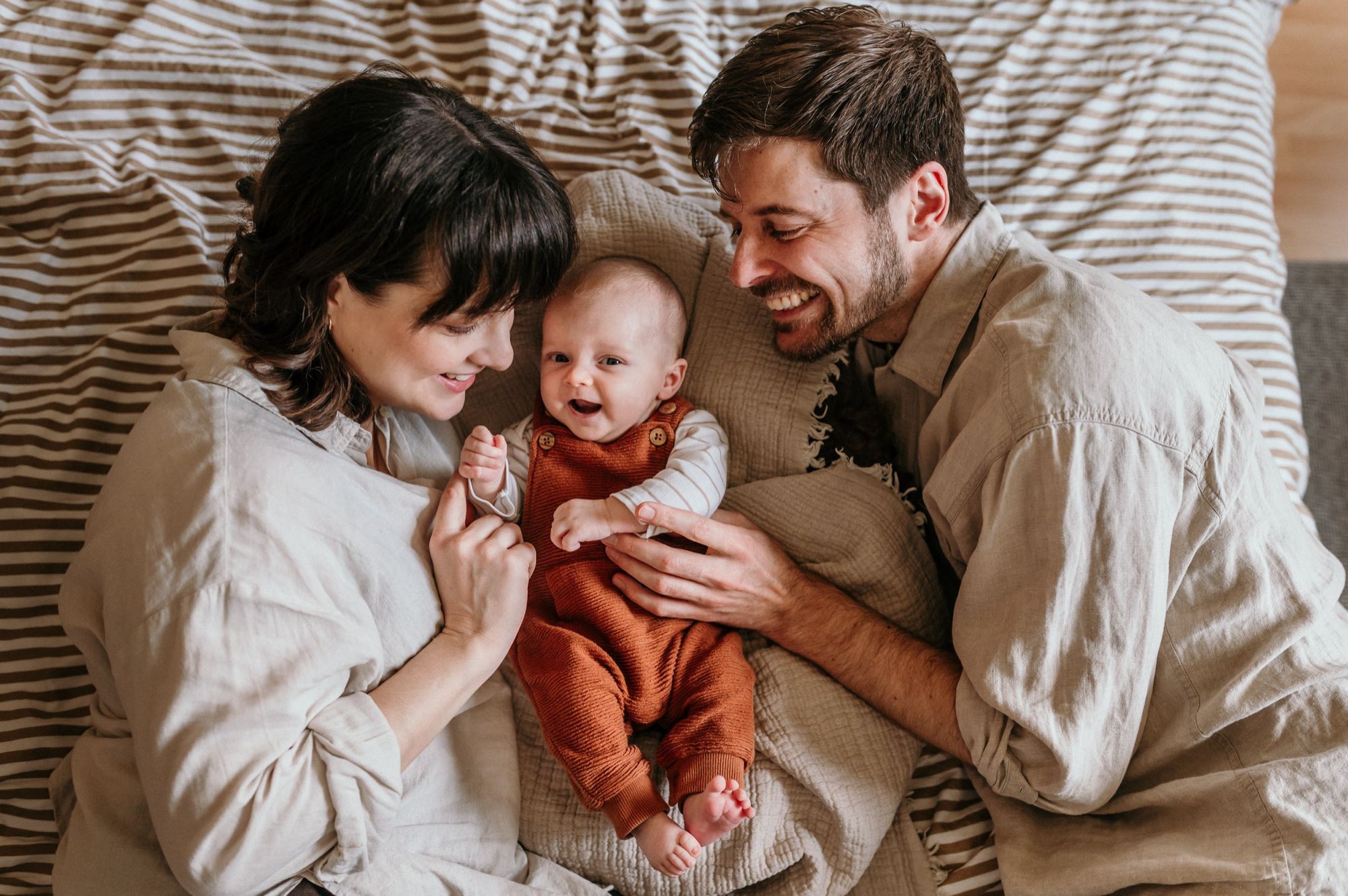 Eltern lachen mit ihrem Baby auf dem Bett